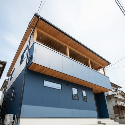 横浜市金沢区の坂道に建つ、2階リビングの開放的なバルコニーを見上げた外観。