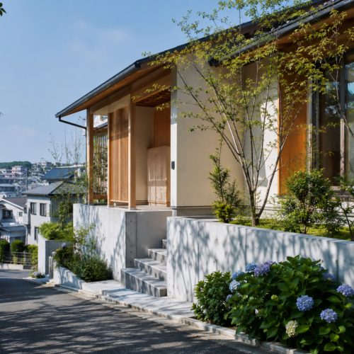 横浜市金沢区の坂道に建つ、コンクリートの高基礎と美しいアプローチ階段を備えたモダンな注文住宅の外観